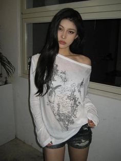 Woman with long black hair wearing an off-shoulder top and distressed shorts indoors