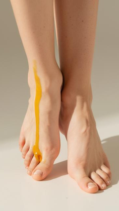 Bare feet with yellow liquid dripping down one leg and foot