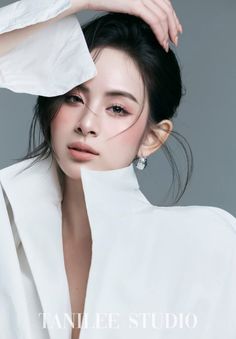 Woman in a white shirt with an updo hairstyle posing in a studio