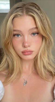 Blonde woman with blue eyes and natural makeup wearing a necklace