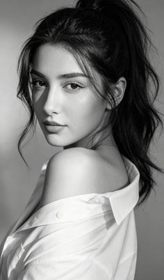 Woman with black hair in a white shirt with one shoulder exposed