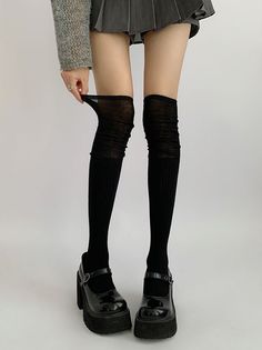 Person wearing black thigh-high socks, a pleated skirt, and platform shoes