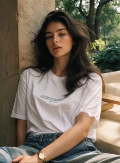Woman with long dark hair wearing a white t-shirt and blue jeans outdoors