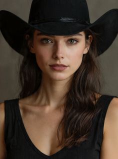 Woman with long dark hair and a black cowboy hat looking directly at the camera