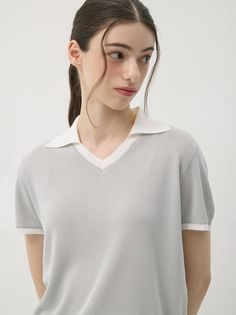 Woman in a light grey polo shirt with a white collar and dark hair in a ponytail