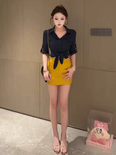Woman in a black cropped shirt and yellow skirt posing indoors