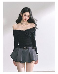 Woman with long dark hair wearing an off-shoulder top and mini skirt