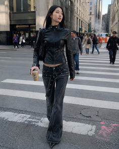 Woman in a black leather jacket and low-rise jeans walking on a city street