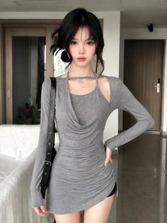 Woman with black hair wearing a gray long-sleeve short dress indoors