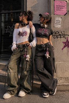 Two women in streetwear posing against a graffiti-covered wall