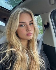 Blonde woman with freckles and blue eyes in a car