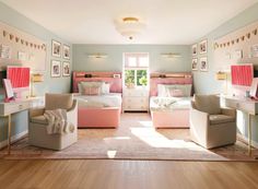 A pastel pink and blue bedroom with twin beds and vanity desks