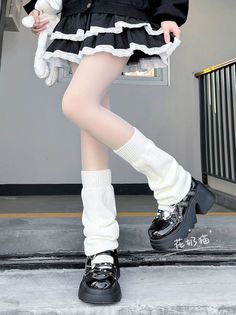 Lower body shot of a person wearing a black skirt, white tights, and platform shoes