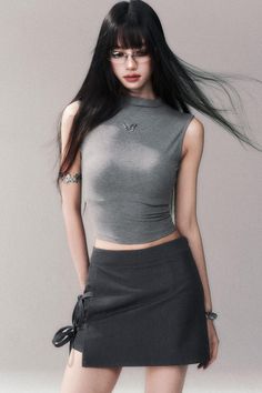 Woman with long black hair and glasses wearing a crop top and mini skirt