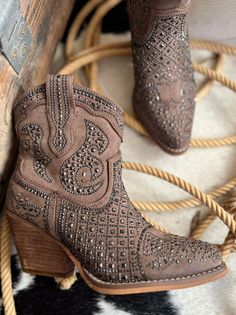 Pair of brown suede cowboy boots with studded details and a rope