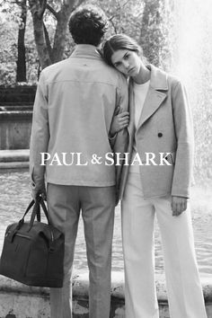 Two people standing by a fountain, one holding a duffel bag