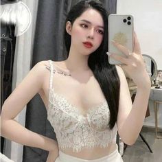 Woman in a white lace top taking a selfie indoors
