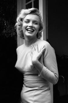 Woman with blonde curly hair in a long sleeve dress, laughing