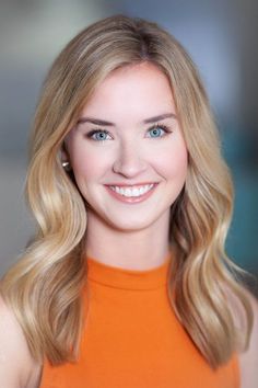 Smiling woman with blonde hair and blue eyes wearing an orange top