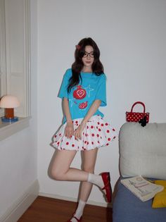 Woman in a blue t-shirt and polka dot skirt posing indoors