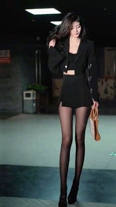Woman in a black mini skirt and cropped blazer with tights and high heels