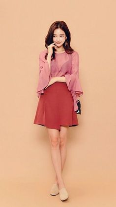 Woman in a pink blouse and red skirt posing in a studio