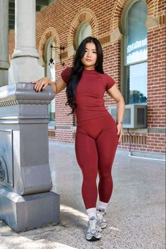 Woman in a red athletic outfit posing outdoors next to a pillar