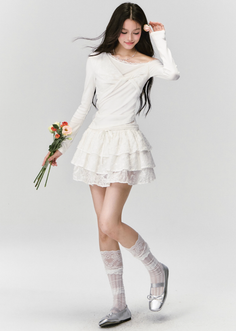 Woman with long dark hair in a white lace outfit holding flowers