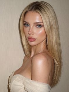 Blonde woman with long hair wearing a strapless top, looking at the camera