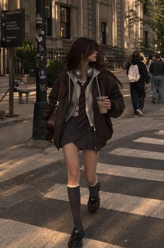 Young woman in a school uniform and brown jacket walking on a city street