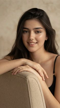 Woman with long dark hair wearing a black top and gold earrings