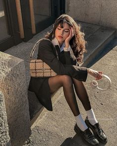 Woman in a suit jacket and tights sitting outdoors during golden hour