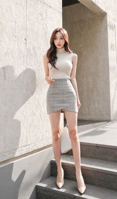 Woman in a plaid skirt and sleeveless top standing on outdoor steps