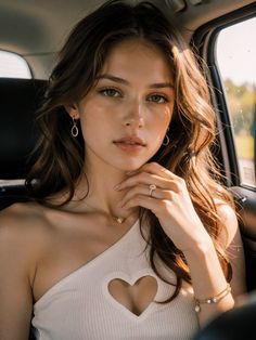 Woman with long hair and jewelry wearing a heart cutout top in a car