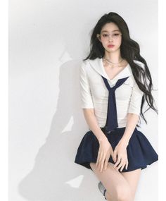 Woman in a school uniform with long dark hair and glasses posing indoors
