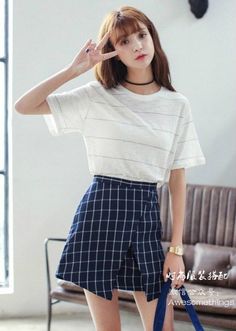Woman in a white striped t-shirt and plaid skirt making a peace sign