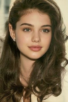 Close-up portrait of a young woman with long wavy brown hair and green eyes