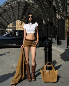 Woman in a white crop top and brown shorts standing outdoors