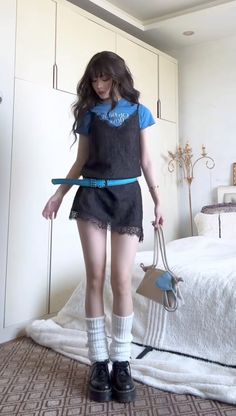 Woman in a black slip dress over a blue t-shirt with a blue belt and leg warmers