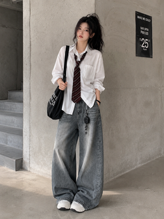 Woman in a white shirt and baggy jeans with a striped tie and high ponytail