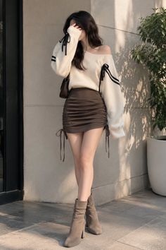 Woman in an off-shoulder sweater and mini skirt posing outdoors