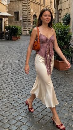 Woman in a lace top and midi skirt walking on a cobblestone street