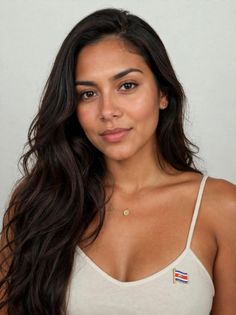 Woman with long dark hair wearing a white tank top and a Costa Rica flag pin
