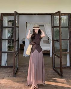 Woman in a straw hat and maxi skirt standing in a doorway