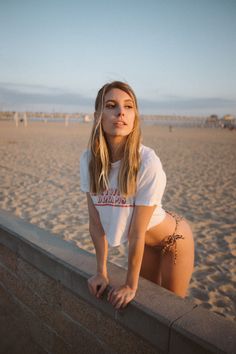 Woman in a cropped t-shirt and leopard print bikini on a beach at golden hour