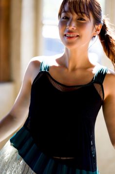 Woman with a ponytail smiling in a black top with sheer details