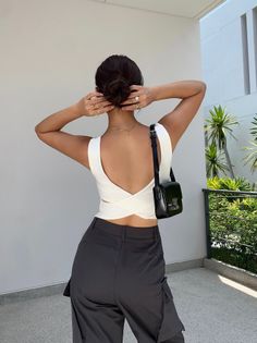 Woman with dark hair in an updo wearing a white top and cargo pants outdoors
