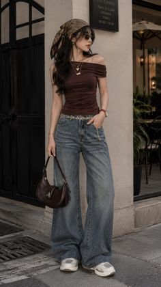 Woman in an off-shoulder top, wide-leg jeans, and a head scarf standing outdoors