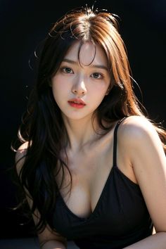 Woman with long hair and a black top against a dark background
