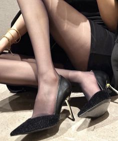 Woman in black pantyhose and high heels with a gold bracelet